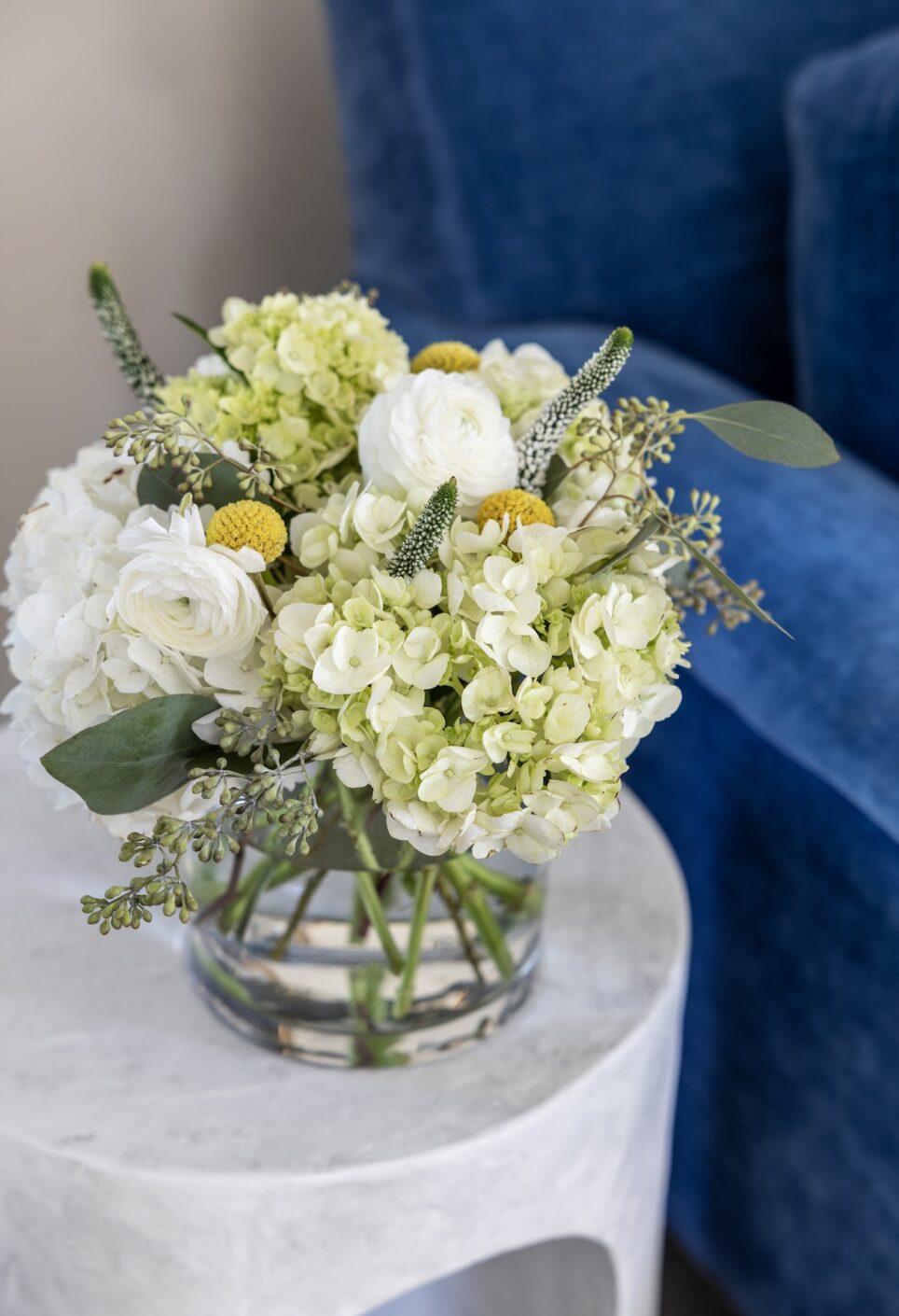 Vase Of Flowers Next To Blue Sofa